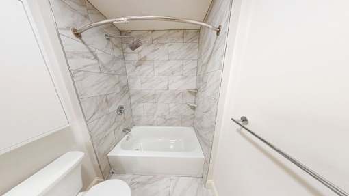A white bathroom with a tub, toilet, and shower.