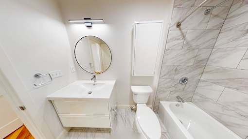 A white bathroom with a marble tile shower.
