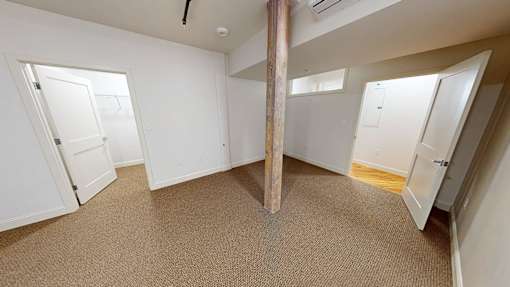 A room with a carpeted floor and a large pillar in the middle.