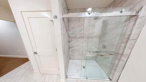 A bathroom with a walk-in shower and a white door.