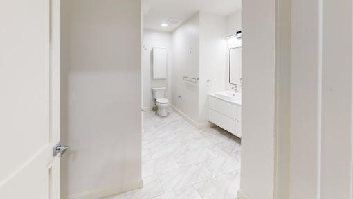 A white bathroom with a toilet, sink, and mirror.