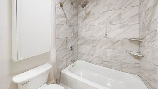 A white bathroom with a tub and toilet.