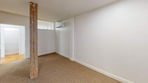 A room with a carpeted floor and a wooden pillar.