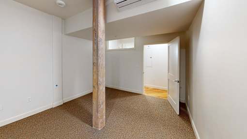 A room with a carpeted floor and a wooden pillar.