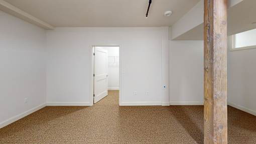A room with a carpeted floor and a wooden pillar.