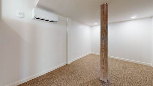 A room with a carpeted floor and a wooden pillar.