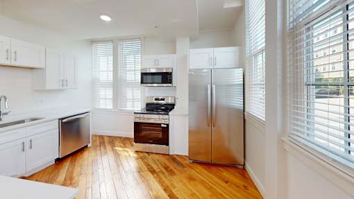 A modern kitchen with wooden floors and stainless steel appliances.