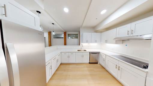 A modern kitchen with white cabinets and a stainless steel refrigerator.