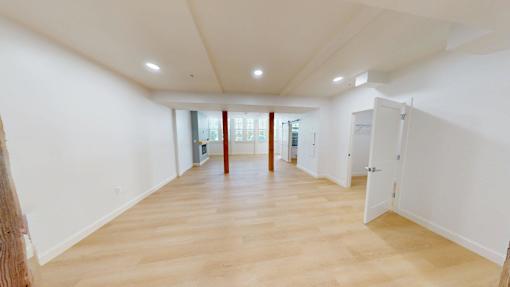 A large empty room with wooden floors and white walls.