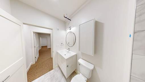 A white bathroom with a toilet, sink, and mirror.
