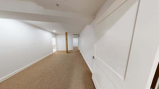 A long hallway with white walls and carpeted floor.
