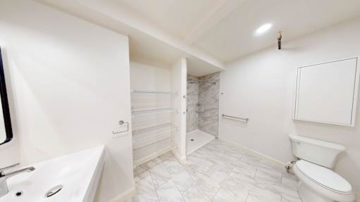 A white bathroom with a toilet, sink, and shower.