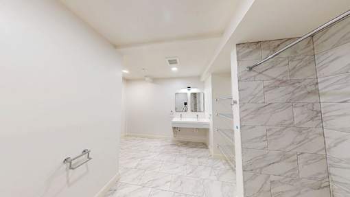 A white bathroom with a marble tile shower.