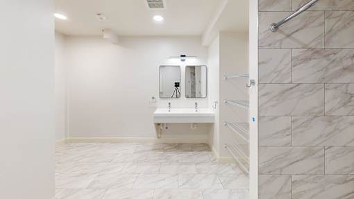 A bathroom with a white sink and marble tiles.