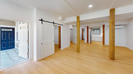 A room with wooden floors and white walls with a blue door.