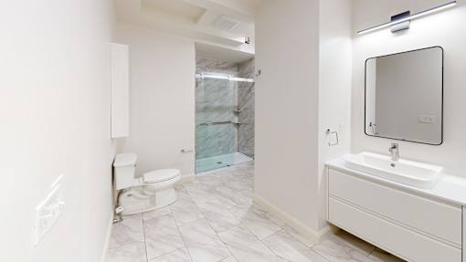 A bathroom with a toilet, sink, and mirror.