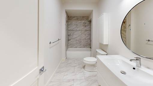 A white bathroom with a marble tile shower.