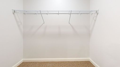 Empty white closet with a metal rack.