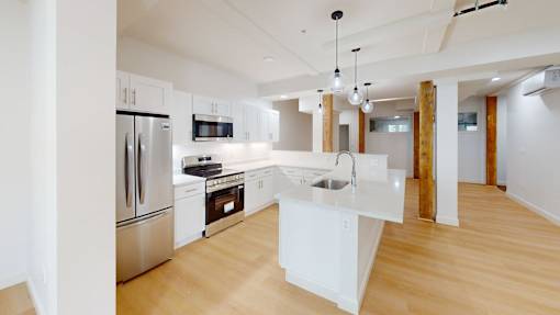 A modern kitchen with wooden floors and stainless steel appliances.
