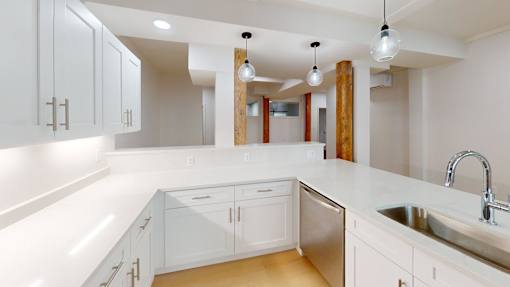 A kitchen with white cabinets and a stainless steel sink.