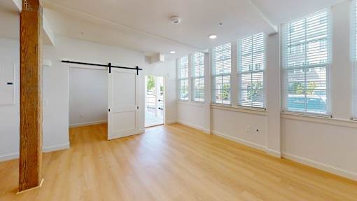 A room with wooden floors and a large window with blinds.
