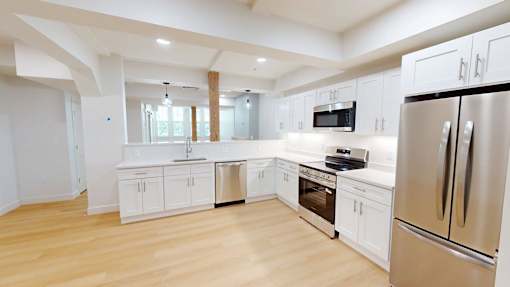 A modern kitchen with wooden floors and stainless steel appliances.