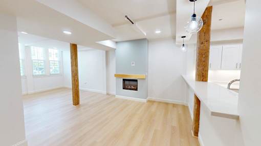 A spacious living room with a fireplace and wooden floors.