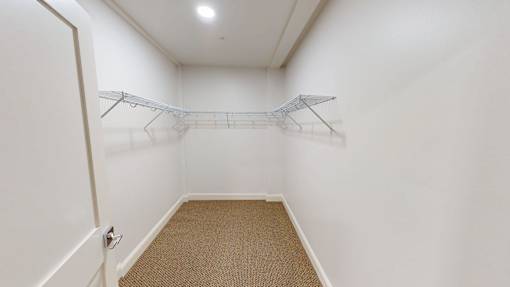 A white closet with a carpeted floor and a single hanger.