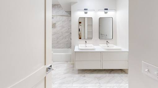 A bathroom with two sinks and a marble wall.