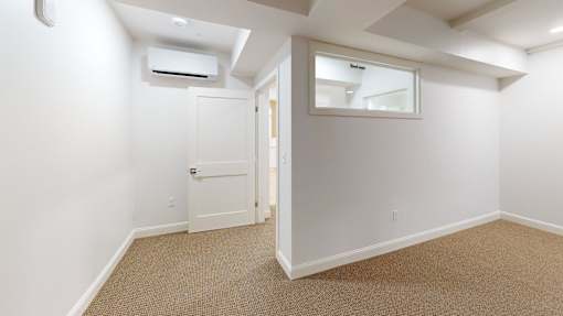 A room with a carpeted floor and a door leading to another room.