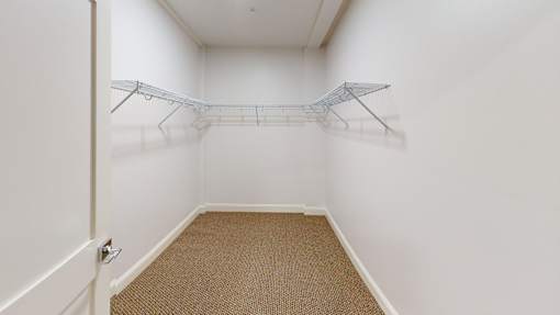 A white hallway with a carpeted floor and a coat rack.