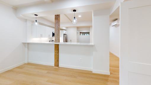 A kitchen with white cabinets and a wooden beam.