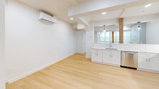 A kitchen with white cabinets and a wooden floor.