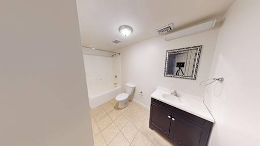 A bathroom with a toilet, sink, and mirror.