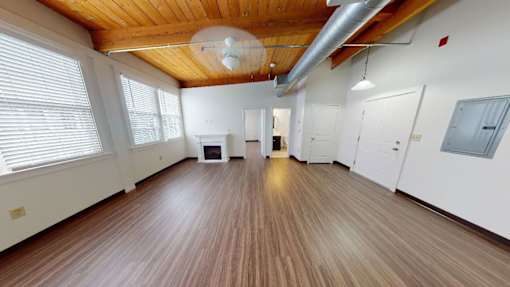 A spacious room with wooden floors and white walls.