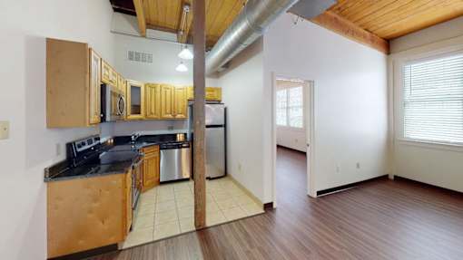 A kitchen with wooden cabinets and a stainless steel refrigerator.