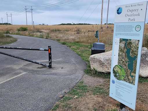 A sign for the Back River Trail stands next to a paved path.