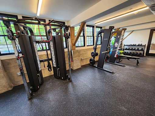 A gym with a variety of equipment including a squat rack, a leg press machine, and a cable machine.
