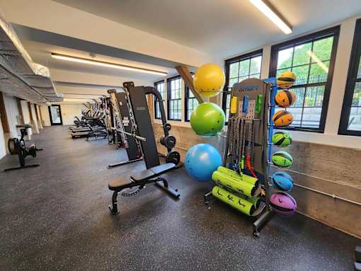 A gym with a variety of equipment including weights and exercise balls.