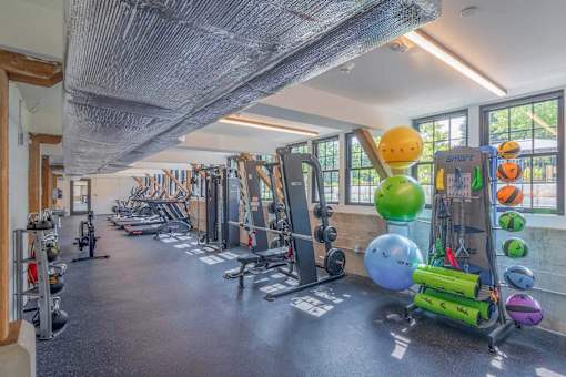 A gym with a variety of equipment including weights and exercise balls.