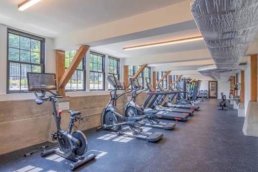 A gym with a row of stationary bikes and treadmills.