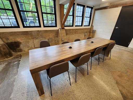 A long wooden table with chairs is in a room with a black door.
