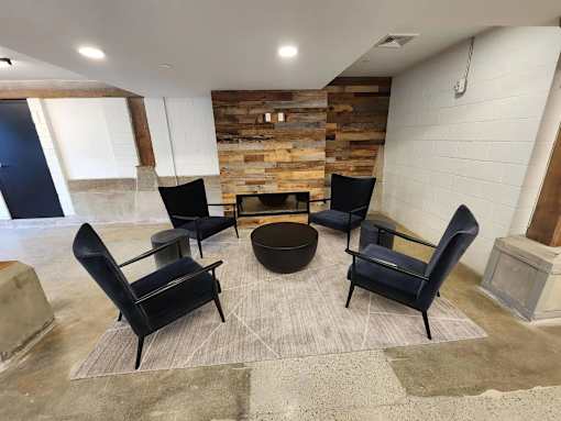 A room with a stone wall and a round table surrounded by chairs.