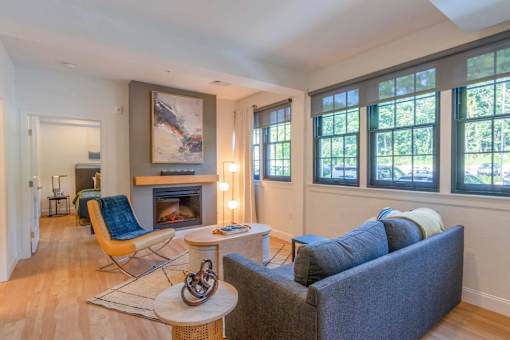 A living room with a fireplace, a blue couch, and a painting on the wall.