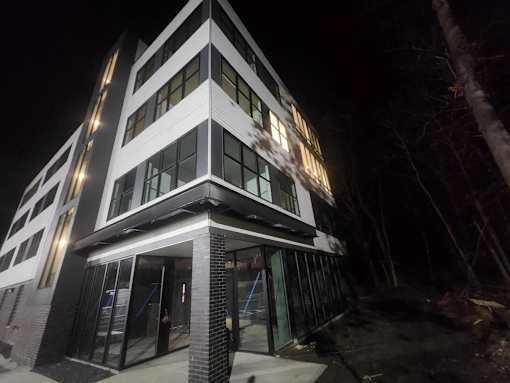 A modern building with a black and white facade is illuminated at night.