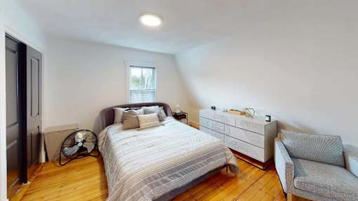 A bedroom with a bed, a couch, and a fan.