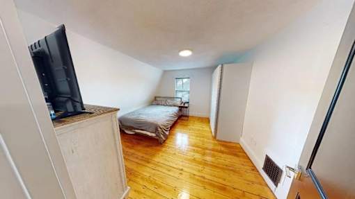 A room with a bed, a television, and a window.