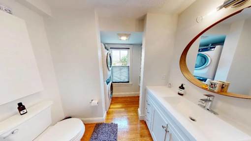 A bathroom with a toilet, sink, and mirror.