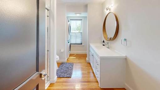 A bathroom with a white vanity and a round mirror.