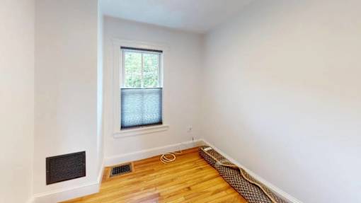 A room with a window and a vent on the wall.
